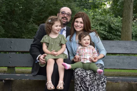 Jewish family of four sitting on a park bench together