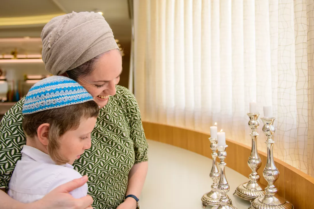 Jewish mother and son lighting Shabbat candles together